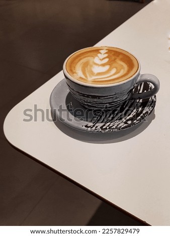 A cup of cappucinno on the white table, latte art
