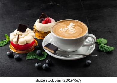 Cup of capuccino and cupcakes on wooden background