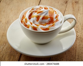 Cup Of Caramel Cappuccino Coffee On Wooden Table