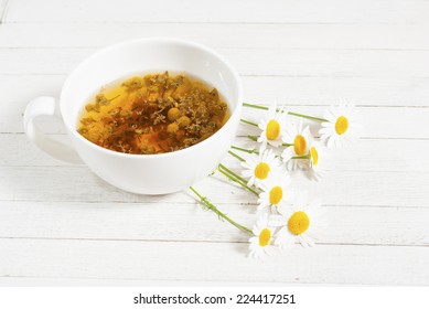 Cup Of Chamomile Tea On White Wooden Table