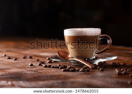 Cup of coffe with milk on a dark background. Hot latte or Cappuccino prepared with milk on a wooden table with copy space