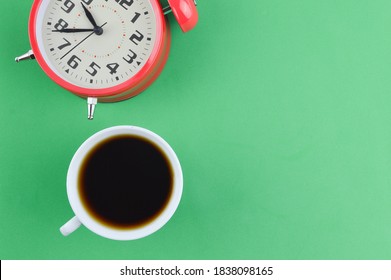 Cup of coffee and alarm clock isolated on a green background with copy space. Business concept. Flat lay view. - Shutterstock ID 1838098165