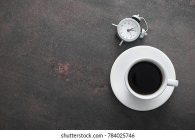 Cup of coffee with alarm clock on table, office break concept, vintage concrete background - Shutterstock ID 784025746