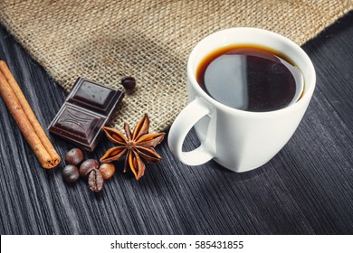 Cup of coffee with anise, chocolate and cinnamon on a wooden table