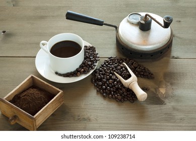 Cup Of Coffee With Bean And Old Coffee Roaster, Wooden Table