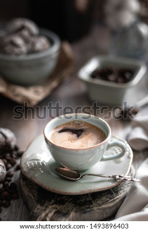 A cup of coffee with coffee beans and chocolate chip cookie on a beautiful brown background. Dark