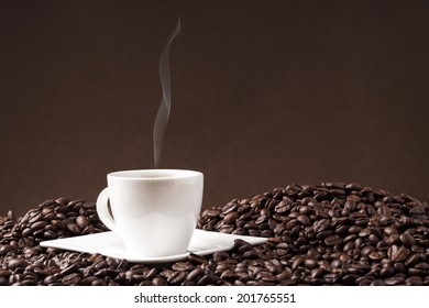 cup of coffee and coffee beans on a brown background with added smoke