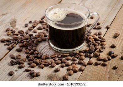 The cup of coffee and  coffee beans on  wooden table 