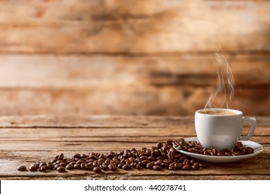 Cup Of Coffee With Beans On Wooden Table