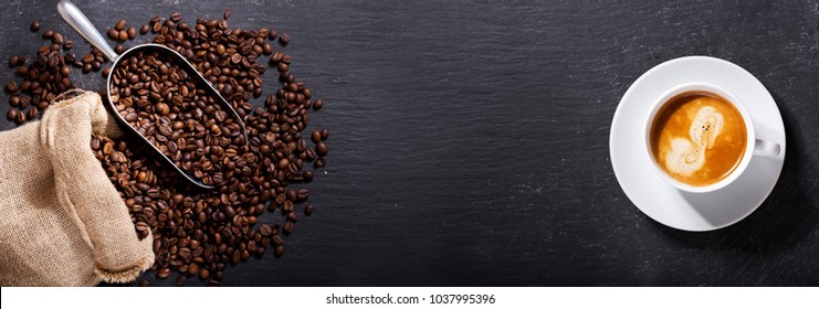 cup of coffee and coffee beans in a sack on dark background, top view - Shutterstock ID 1037995396