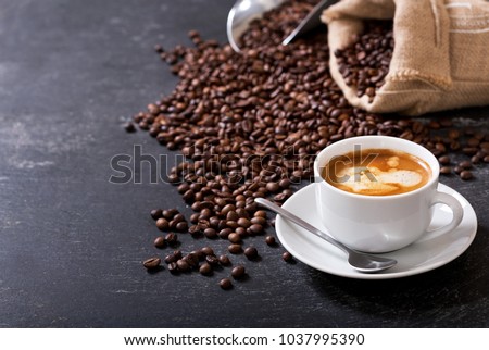 cup of coffee and coffee beans in a sack on dark background