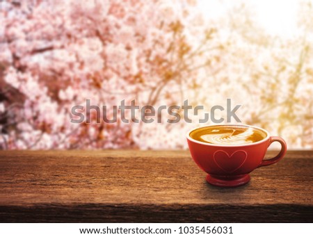 Cup of coffee with beautiful latte art on wooden table with sakura or cherry blossom background
