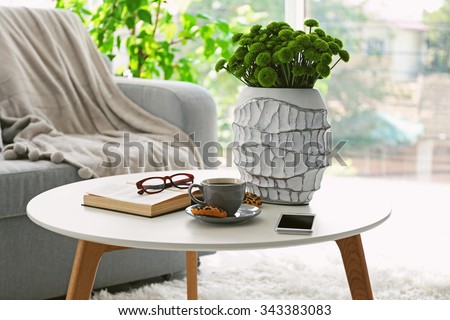 Cup of coffee with biscuits on table in room