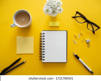 A Cup Of Coffee, A Blank Notebook, Reading Glasses And Office Supplies On A Yellow Background, Top View, Everyday Office Life