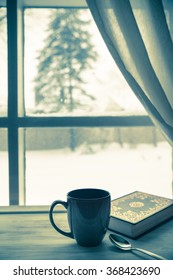 Cup Of Coffee And Book Near Window On A Snowy Winter Day