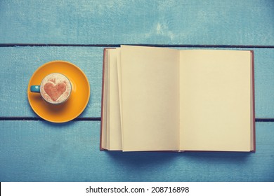 Cup Of Coffee With Book On Blue Wooden Table.