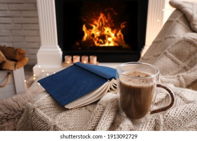 Cup Of Coffee And Book On Plaid Near Fireplace Indoors. Cozy Atmosphere