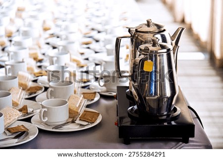 A cup of coffee, bread, and a kettle of hot water are on the table in the conference room.