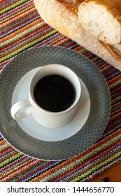 Cup of coffee and bread on a gray plate. Black coffee with bread. Cup with coffee and bread.