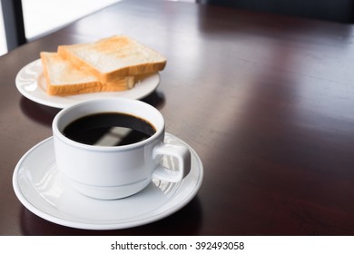A cup of Coffee with bread on table in the morning/selective focus