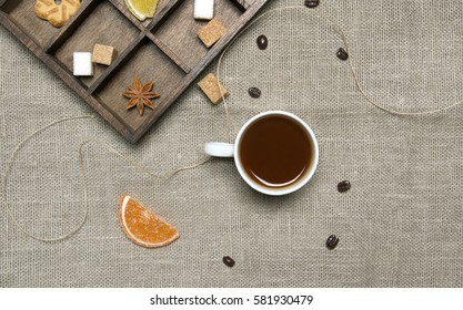 Cup of coffee, candies, coffee beans on linen background