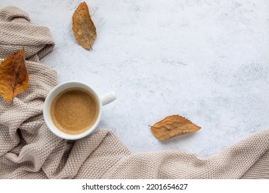 Cup Of Coffee Cappuccino, Beige Sweater And Dry Autumn Leaves On Table Background. Cozy Beige Autumn, Fall Aesthetic. Top View, Flat Lay, Copy Space

