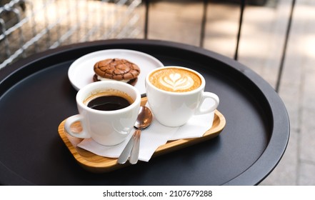 A cup of coffee and a cup of cappuccino with chocolate chip cookies on a table in a street cafe. Coffee break. Close-up. - Powered by Shutterstock