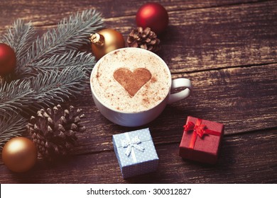 Cup Of Coffee And Christmas Toys With Pine Brench On Wooden Table.