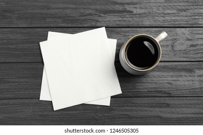 Cup of coffee and clean paper napkins on wooden background, top view
