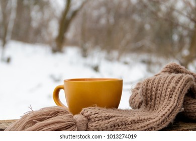 Cup of coffee and cozy knitted scarf on the background of the winter forest - Powered by Shutterstock