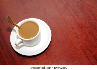 A Cup Of Coffee With Creamer On The Table