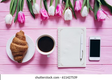 Cup Of Coffee With Croissant, Fresh Tulips, Smartphone And Notebook Sheet Of Paper On Wooden Background For Mother's Day. 