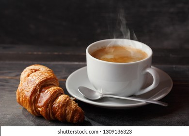 Cup Of Coffee And Croissant On Wooden Table