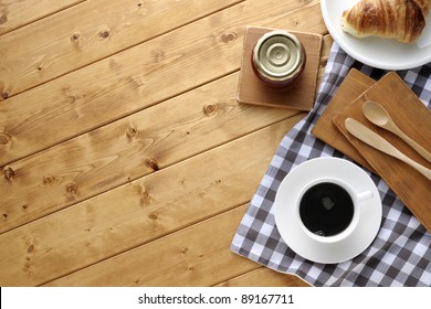 A Cup Of Coffee With Croissant On Wooden Table