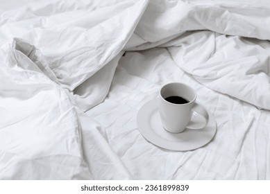 Cup with coffee drink standing on unmade bed with messy crumpled blanket, sheet and pillow. Lifestyle morning concept, coffee in bed. - Shutterstock ID 2361899839