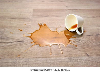 A Cup Of Coffee Fell On Laminate, Coffee Spilled On Floor. Focus On The Puddle.