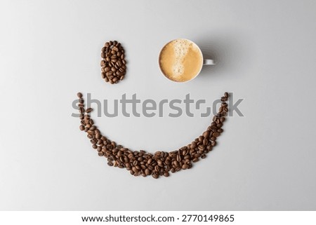 Cup of coffee forms one eye in smiling face made of coffee beans on light background, minimal banner for cheerful cafe branding.