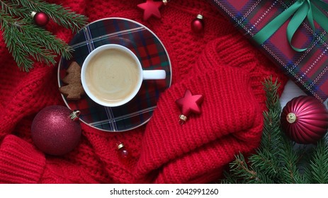 Cup of coffee with gingerbread, Christmas ornaments, wrapped gift and fir branches on red knitted sweater.  - Powered by Shutterstock