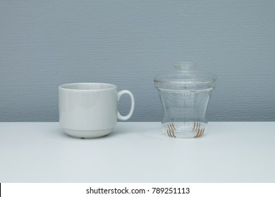 Cup Of Coffee And Glass Teapot On White Tabletop. Minimal Concept