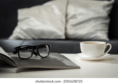 A Cup of Coffee, Glasses, and a Stack of Magazines on a White Tabletop