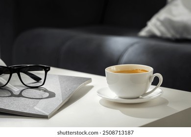 A Cup of Coffee, Glasses, and a Stack of Magazines on a White Tabletop - Powered by Shutterstock