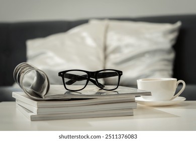 A Cup of Coffee, Glasses, and a Stack of Magazines on a White Tabletop