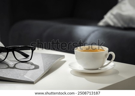 A Cup of Coffee, Glasses, and a Stack of Magazines on a White Tabletop