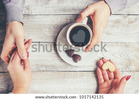 A cup of coffee in the hands of lovers. Silhouette in a cup.  Selective focus. 