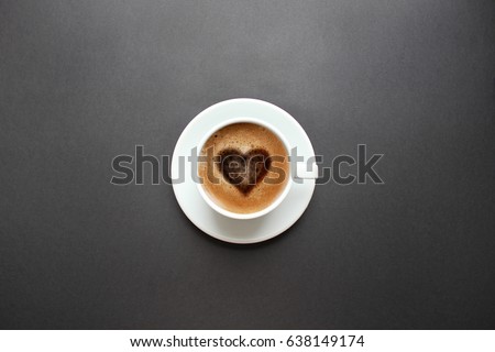 Cup of coffee with heart shape on black background. Top view with copy space.