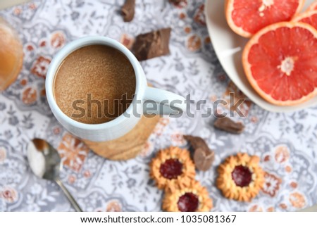 A cup of coffee with homemade cookies, grapefruit slices and chunks of chocolate
