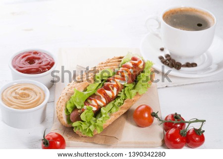 cup of coffee and hotdog on a served white table