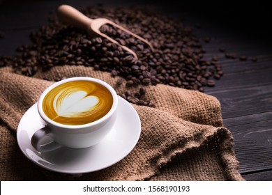 Cup of coffee latte with heart shape and coffee beans on old wooden background - Powered by Shutterstock