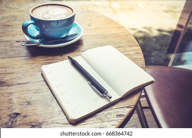 Cup of coffee latte with notepad top view on wooden table/vintage style