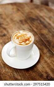 A cup of coffee with leaf pattern in a cup on wooden background 